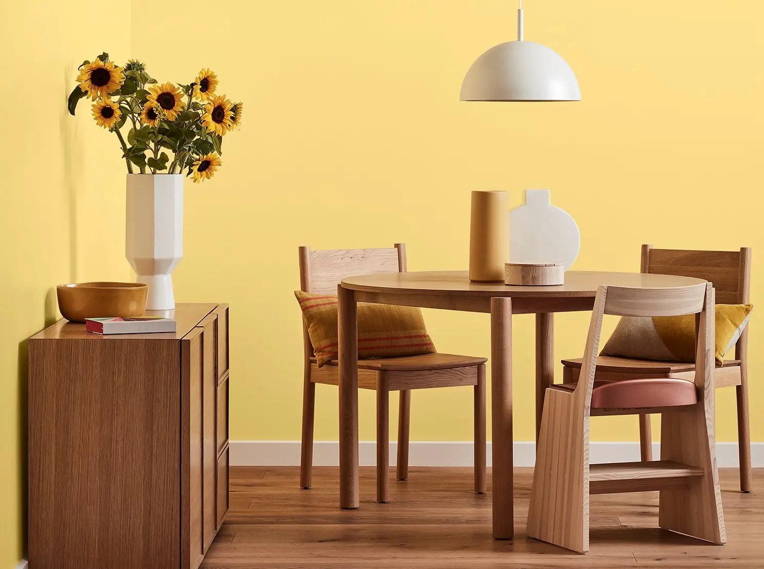 Yellow wall featuring in dining room with decorative items on table and buffet.