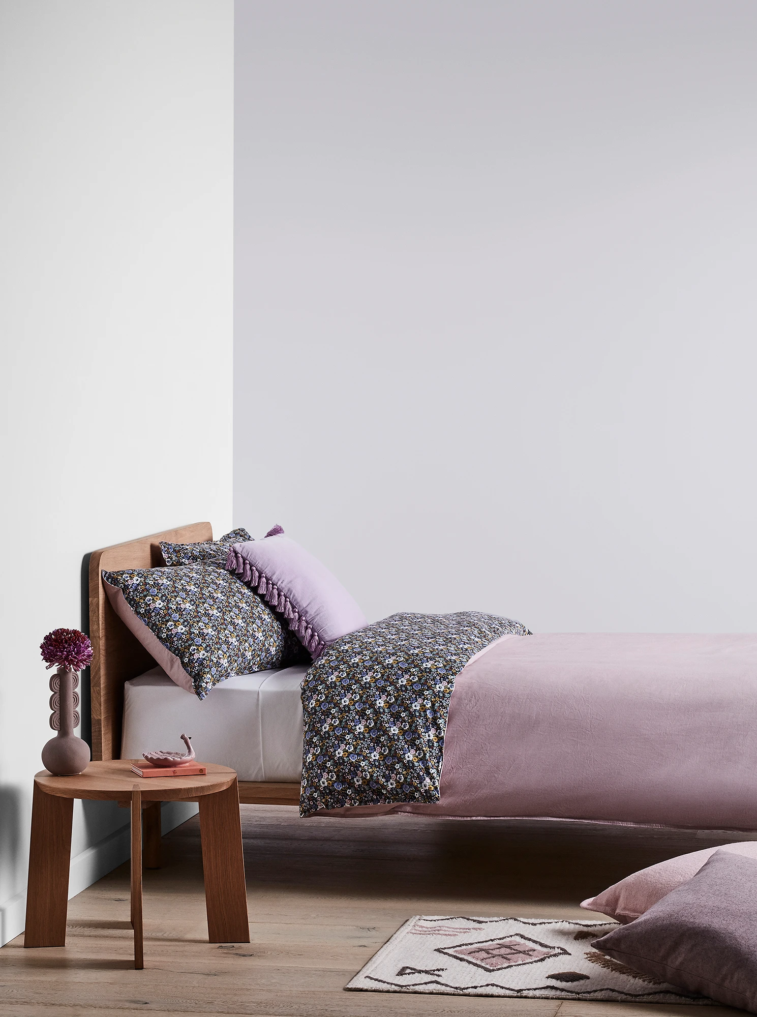 Purple bedroom with timber bed and side table and purple linens.