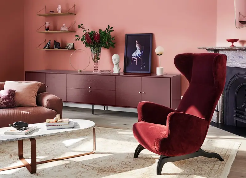 interior pink lounge room with red velvet chair.