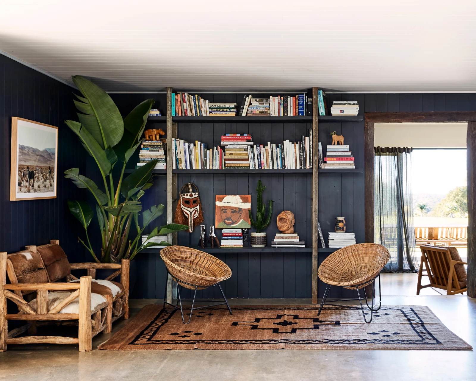 Black wall with wicker chairs and bookshelf