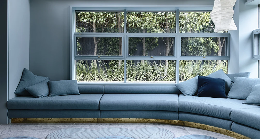 Colour Awards entry Erskine House with blue/green walls and built in sofa in matching colour, with large window behind it.