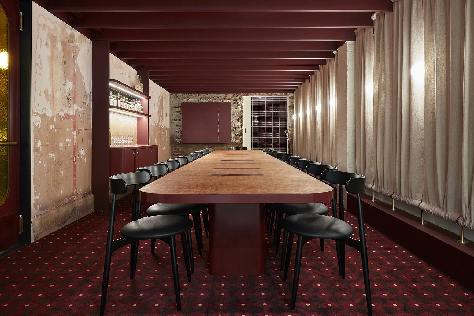 Long dining table in restaurant with red themes.