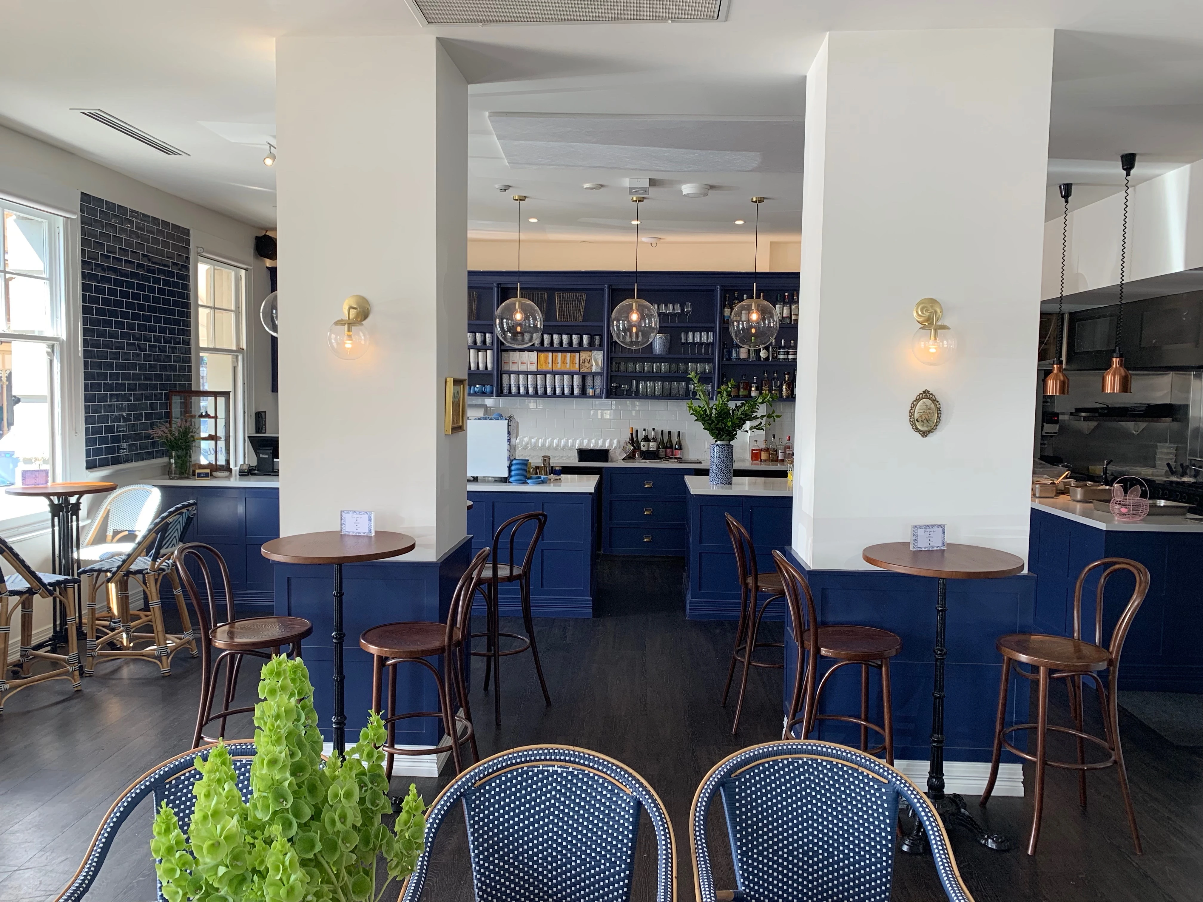 blue and white restaurant with pendant lighting and bentwood chairs.