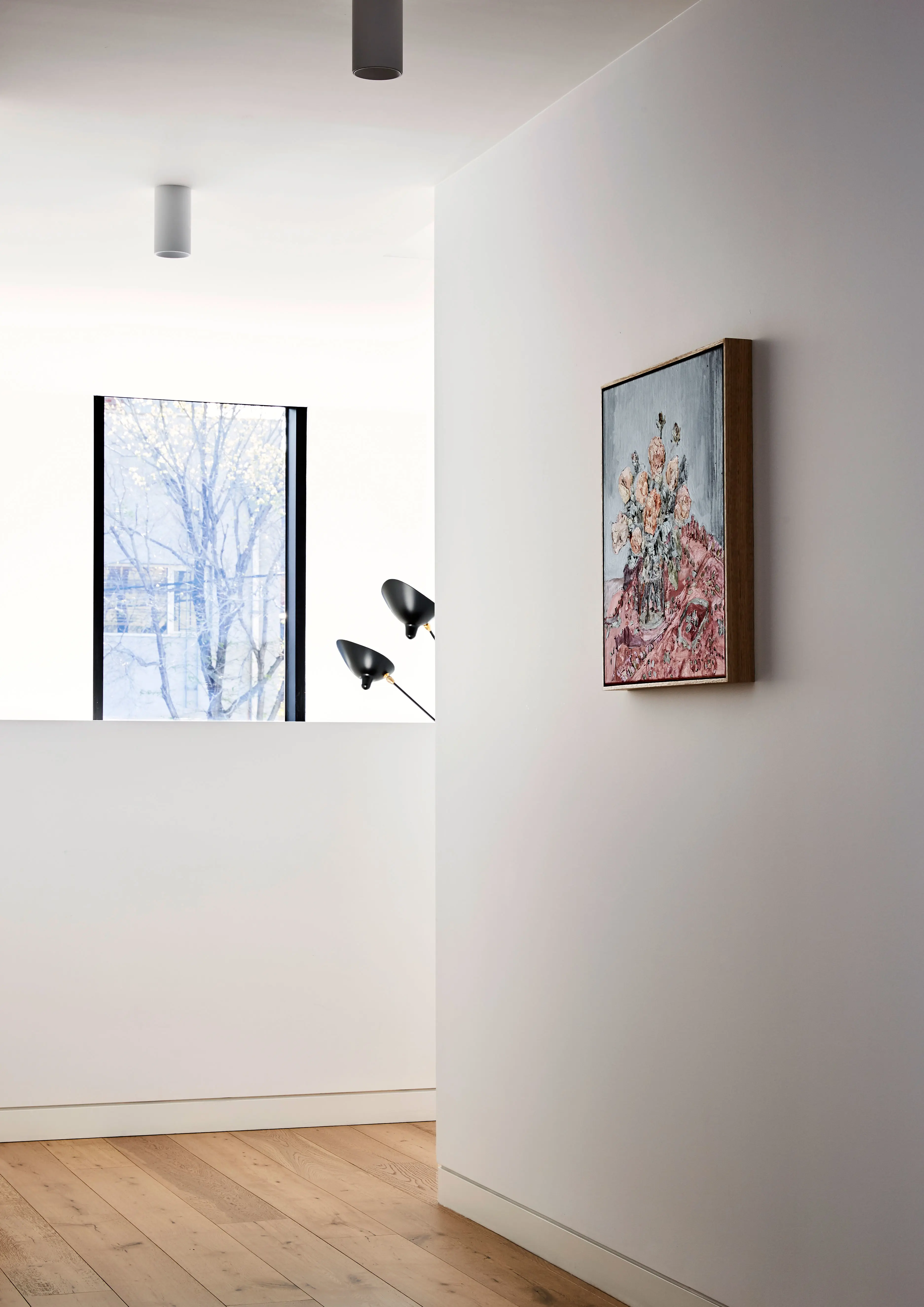 White hallway with artwork and timber floors