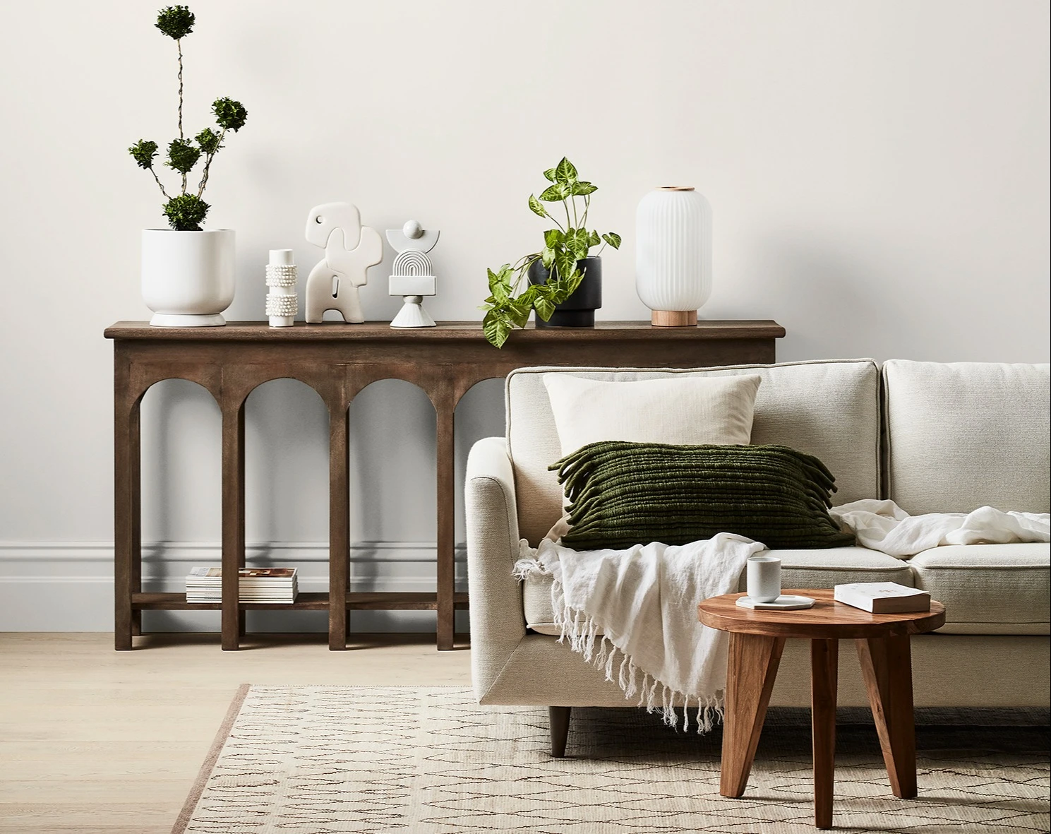 White and neutral themed living room with couch and buffet table against wall with decorative items.