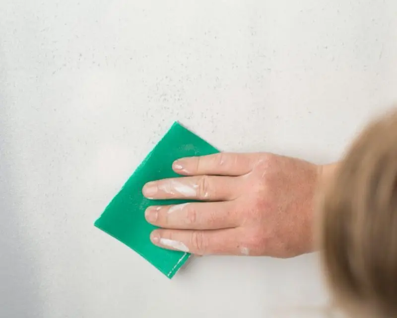 Woman wiping wall with sponge