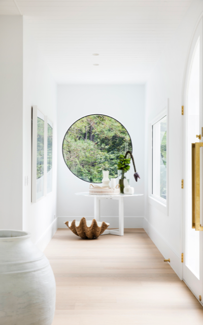 Hinterland Project, NSW. A large round window at the end of hallway in Dulux White on White™. 