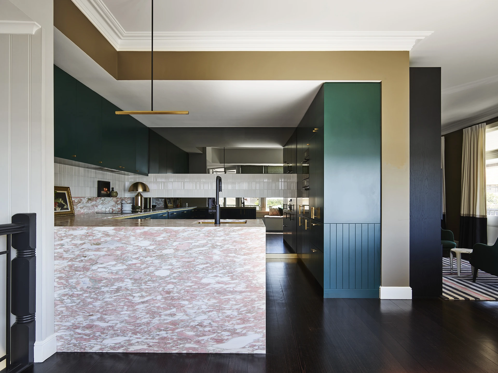 Kitchen with pink marbled bench, navy cabinets, green cabinets, gold trim and white ceiling