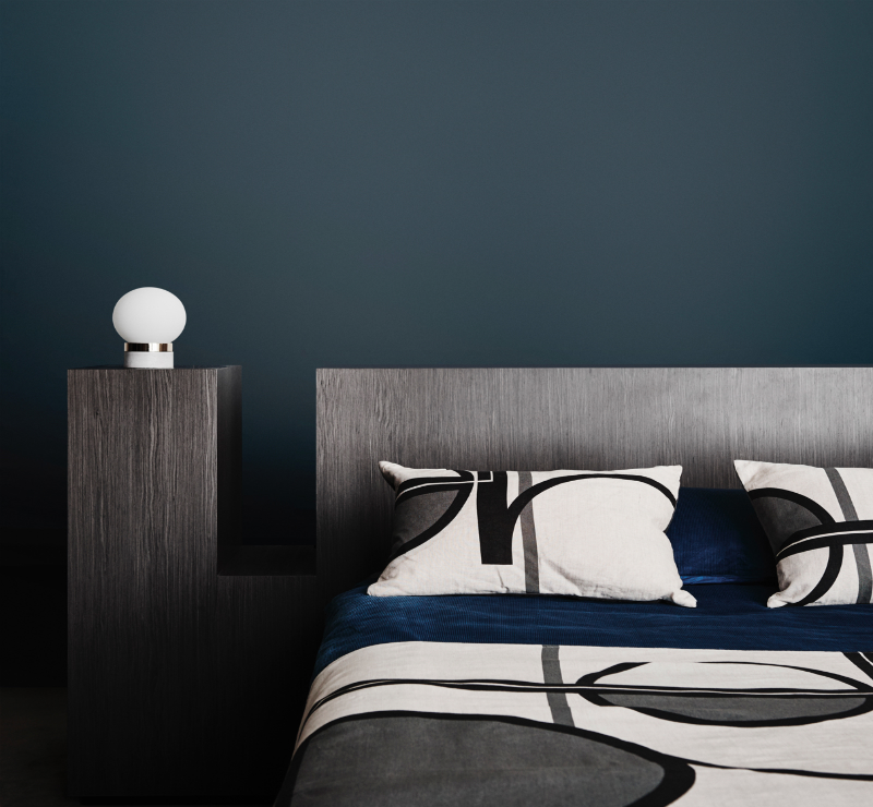 interior dark bedroom with teal walls and lamp.