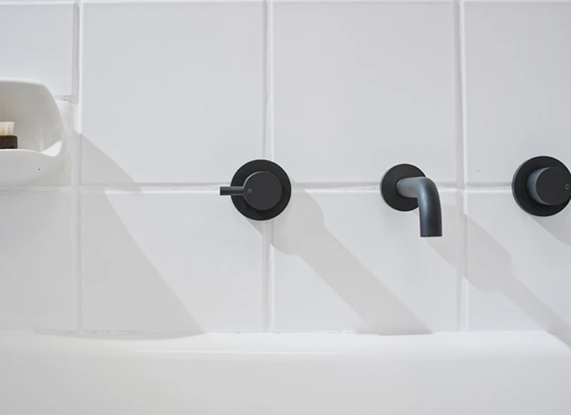 bathroom white tiles with black bathtub taps.