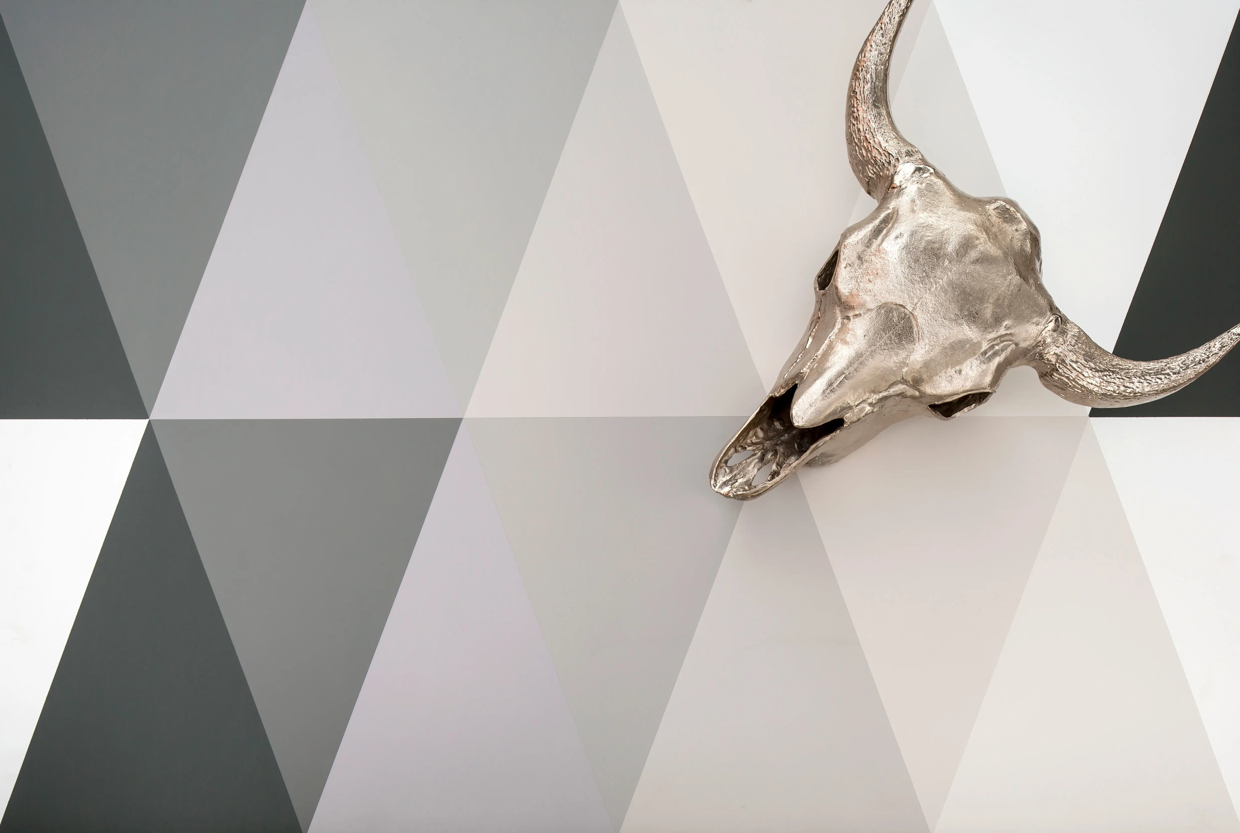 Different shades of grey painted in triangular pattern with silver animal skull.