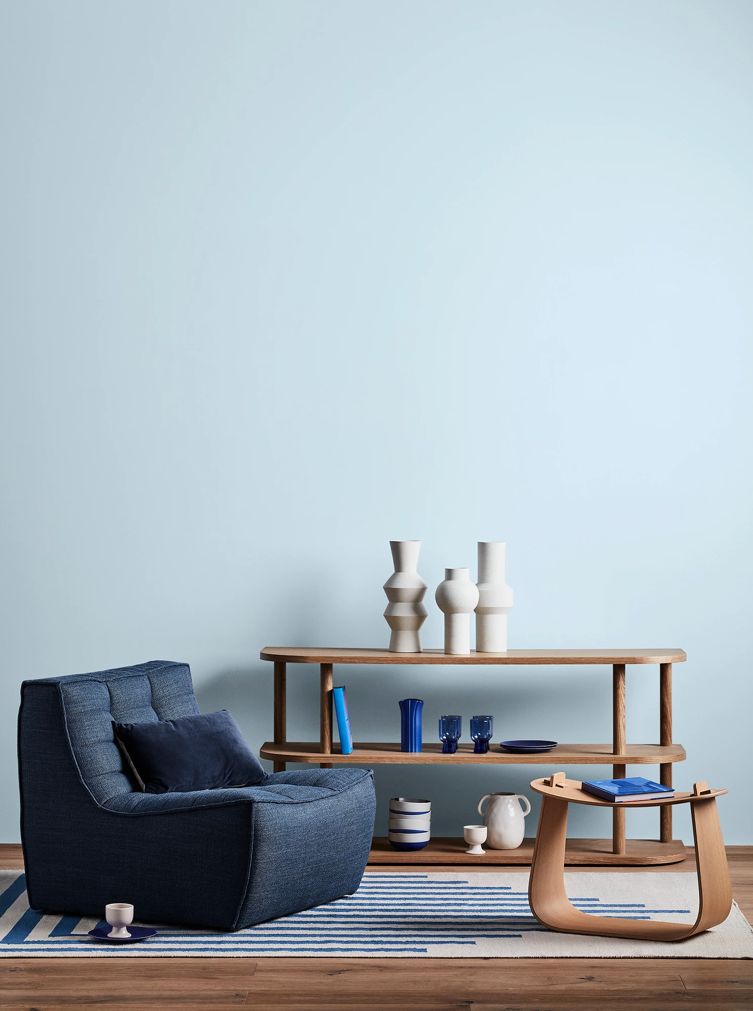 Blue living room with blue armchair, wooden coffee table and shelves with blue and white decor.