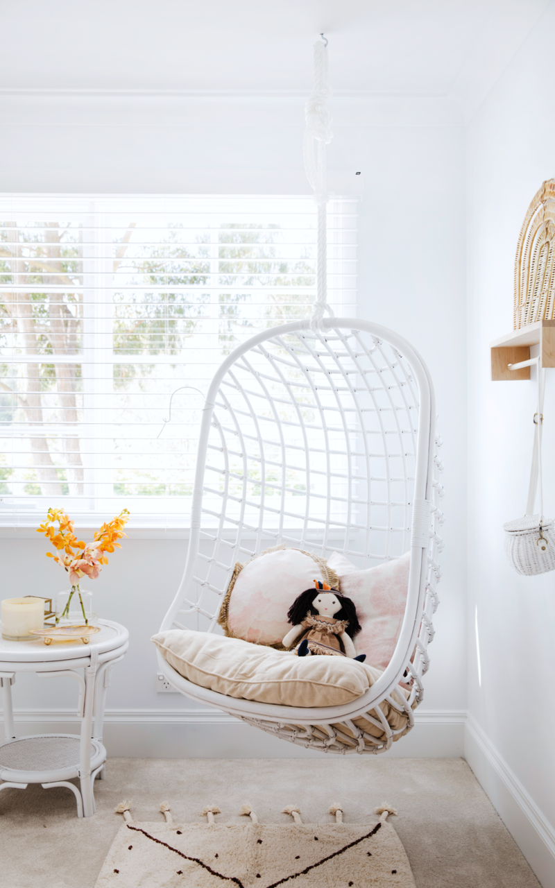 Egg chair in white cane hanging from ceiling in living room painted in Dulux White on White.