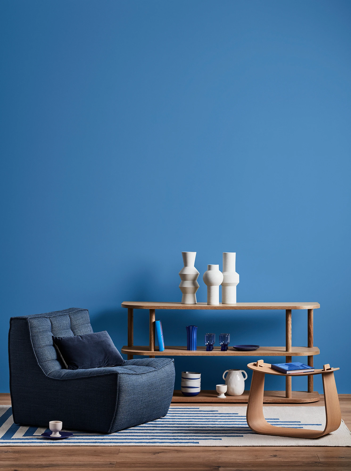 Blue living room with blue armchair, wooden coffee table and shelves with blue and white decor.