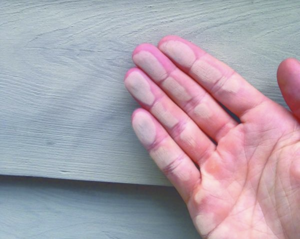 Paint on weatherboards and on a hand with a chalky residue