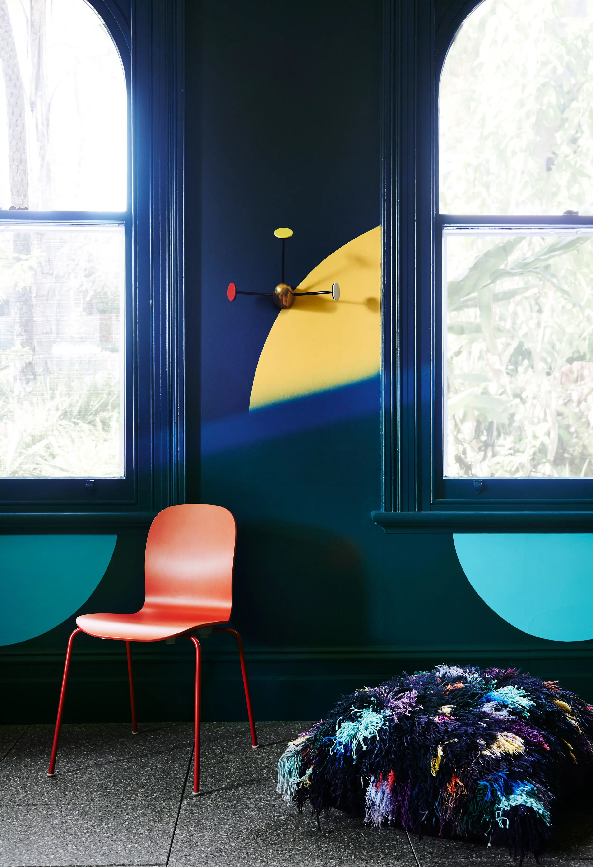 Traditional arched windows in dark blue living room with orange chair