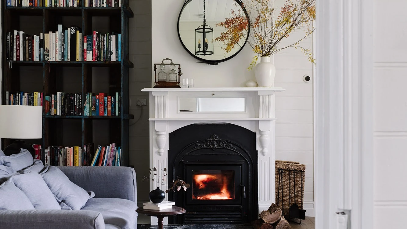 Interior living room painted in white featuring fireplace and bookshelf to the left.