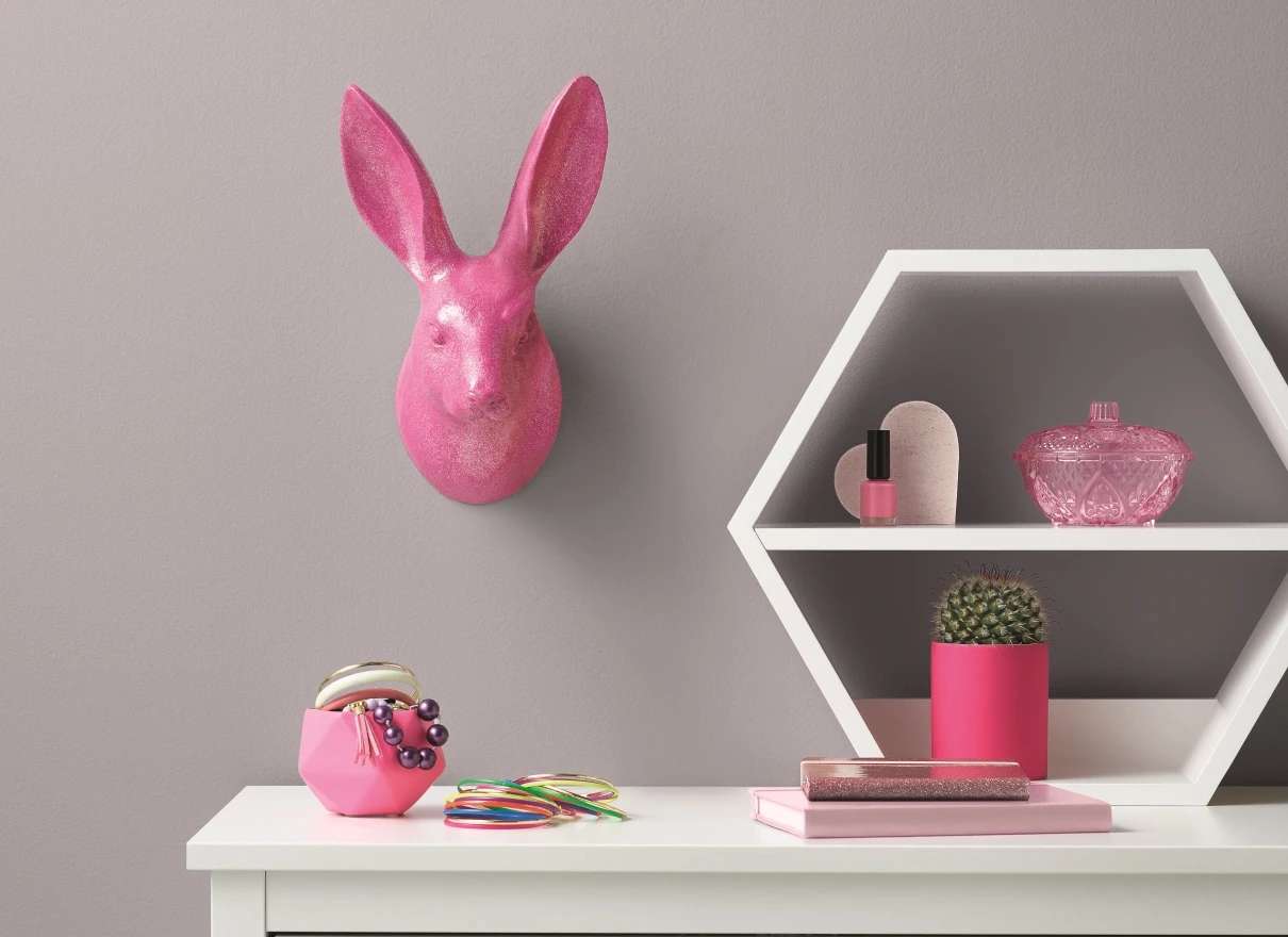pink rabbit head on a wall, white desk with pink ornaments