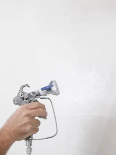 Hand using spray gun to paint white wall resulting in overspray