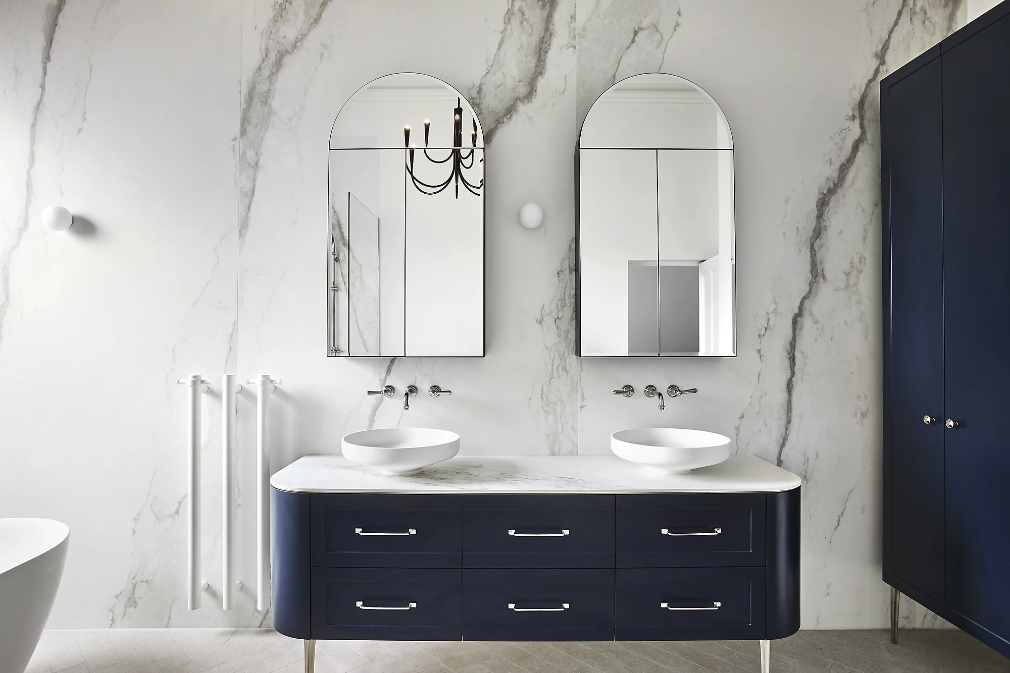 White marble bathroom. Dual sinks on vanity with blue drawers, 