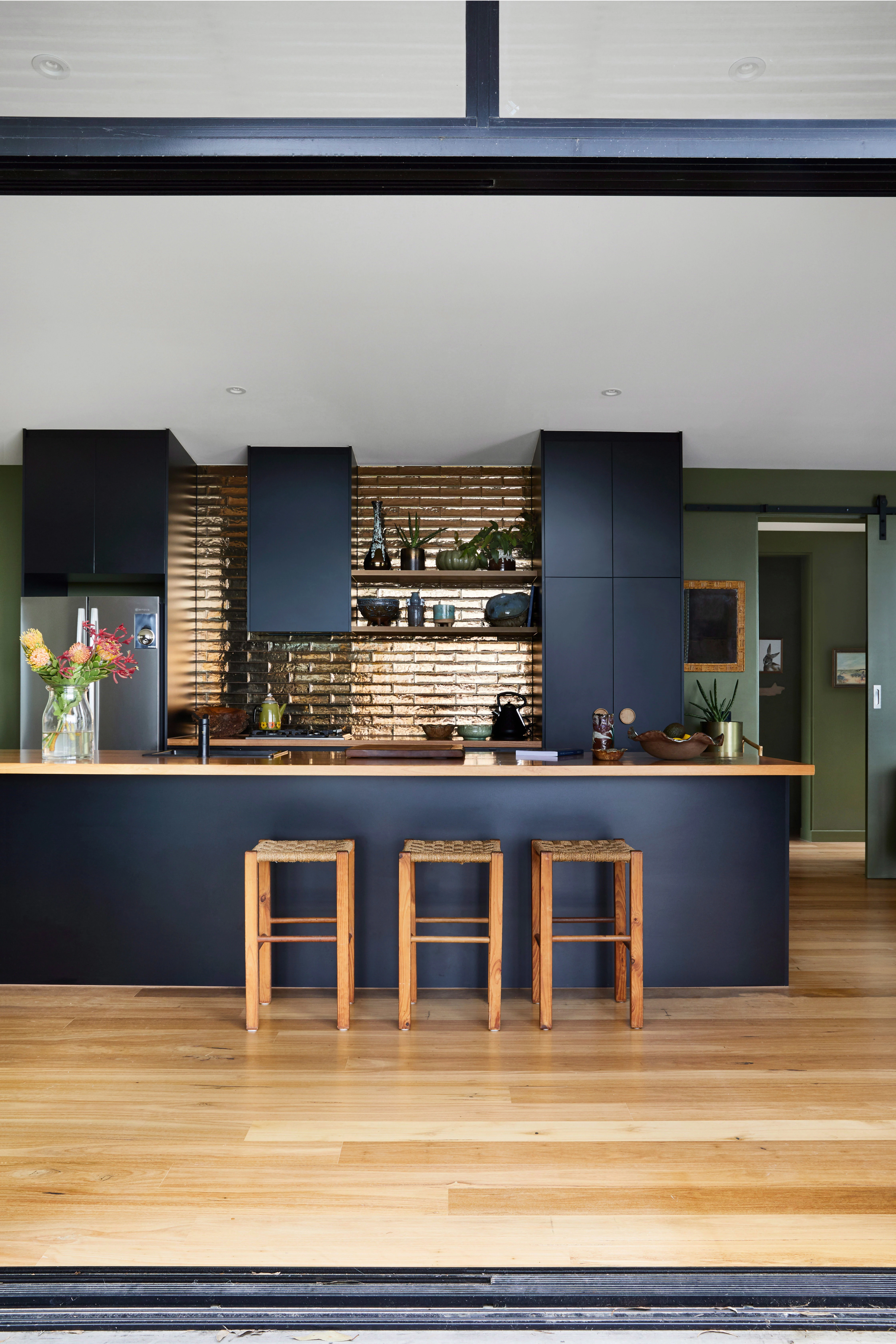 Black kitchen with timber floors and stools.