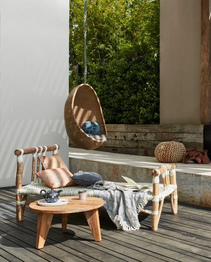 Neutral outdoor space with rendered wall and hanging egg chair
