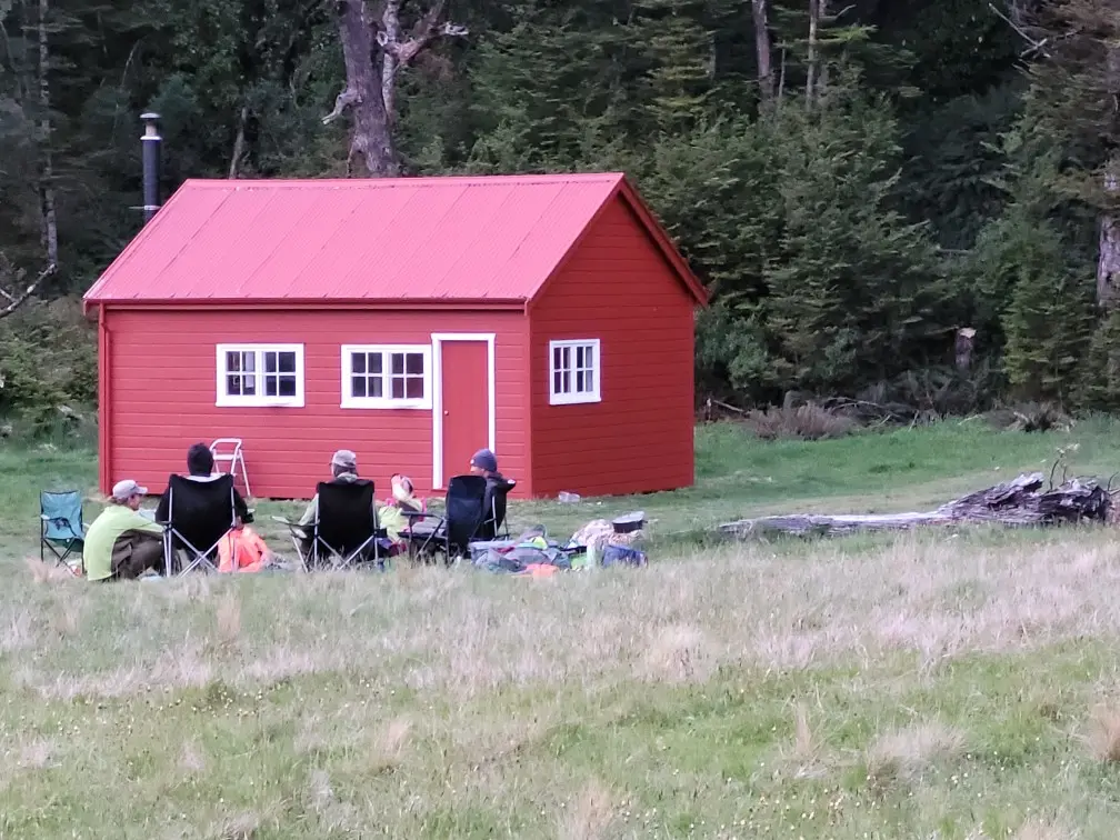 4 people sitting around Red Hut