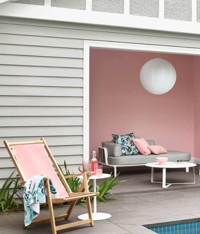 exterior pink pool house with chair and couch.