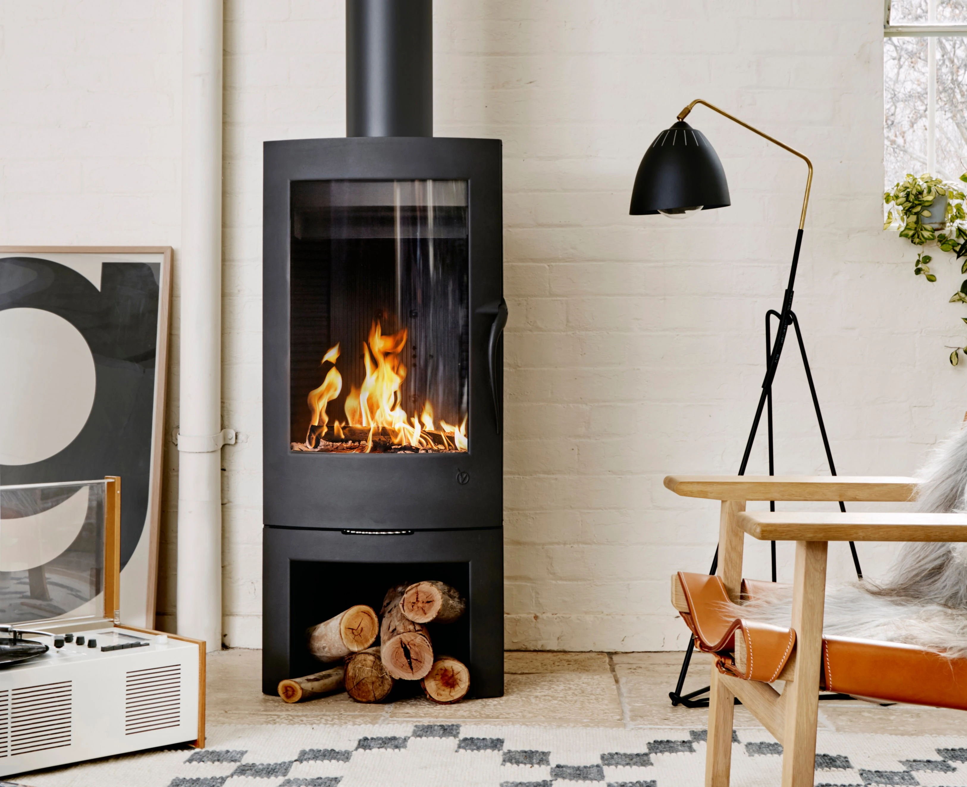 interior closeup of fireplace on white brick wall with lamp and chair. 