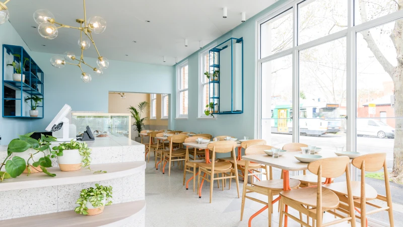 Pale blue-green restaurant with timber chairs and tables