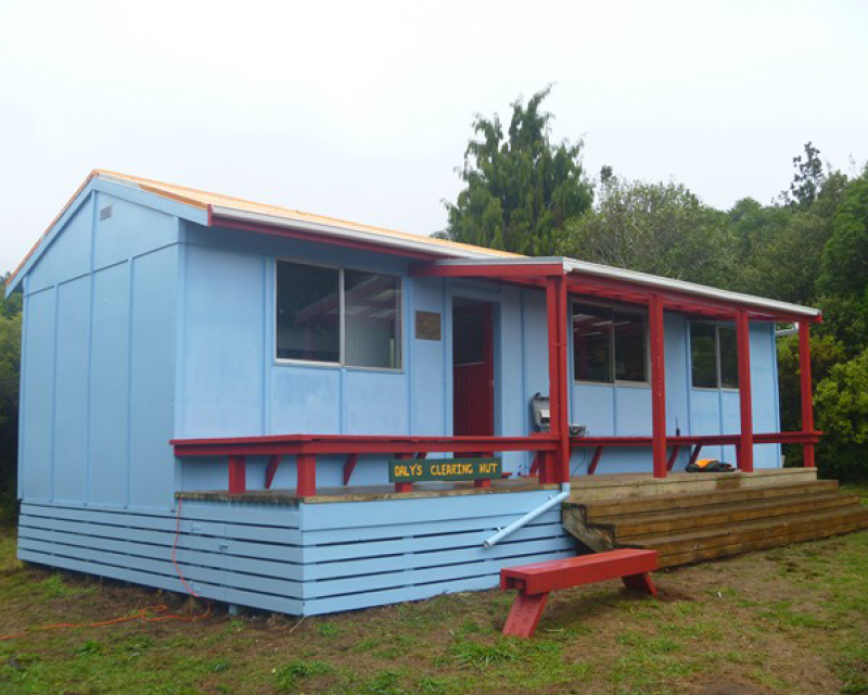 Dalys Clearing Hut is blue with red accents on the benches and banister poles