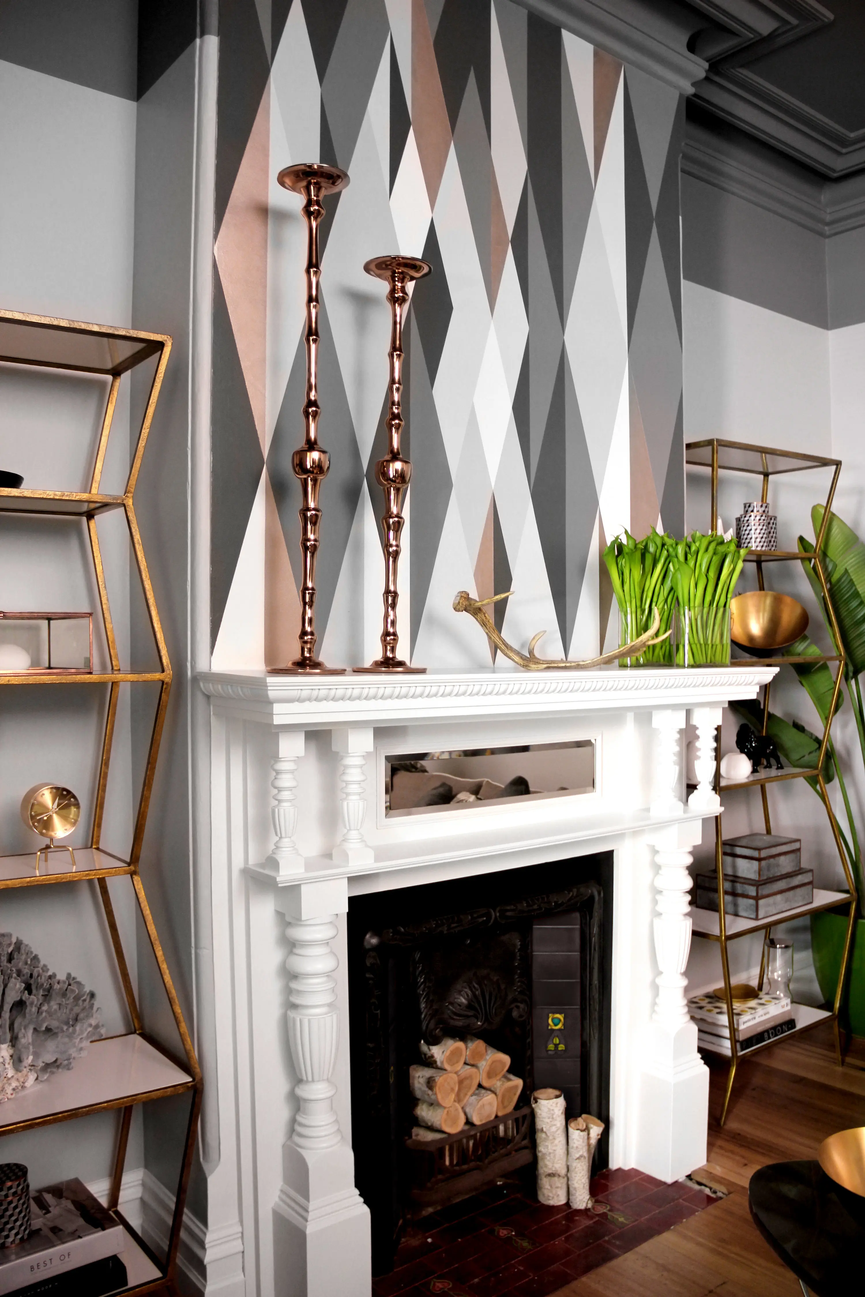Traditional fireplace with white mantle and chimney breast painted in geometric pattern with whites and greys.