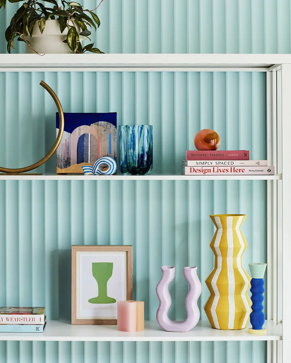 White shelving with light blue fluted background and decor accessories
