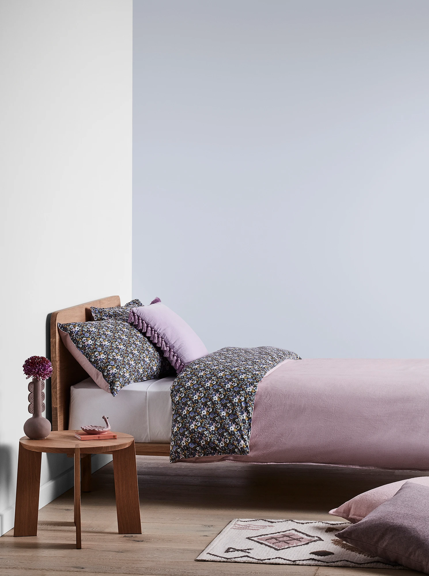 Purple-blue bedroom with timber bed and side table and purple linens.