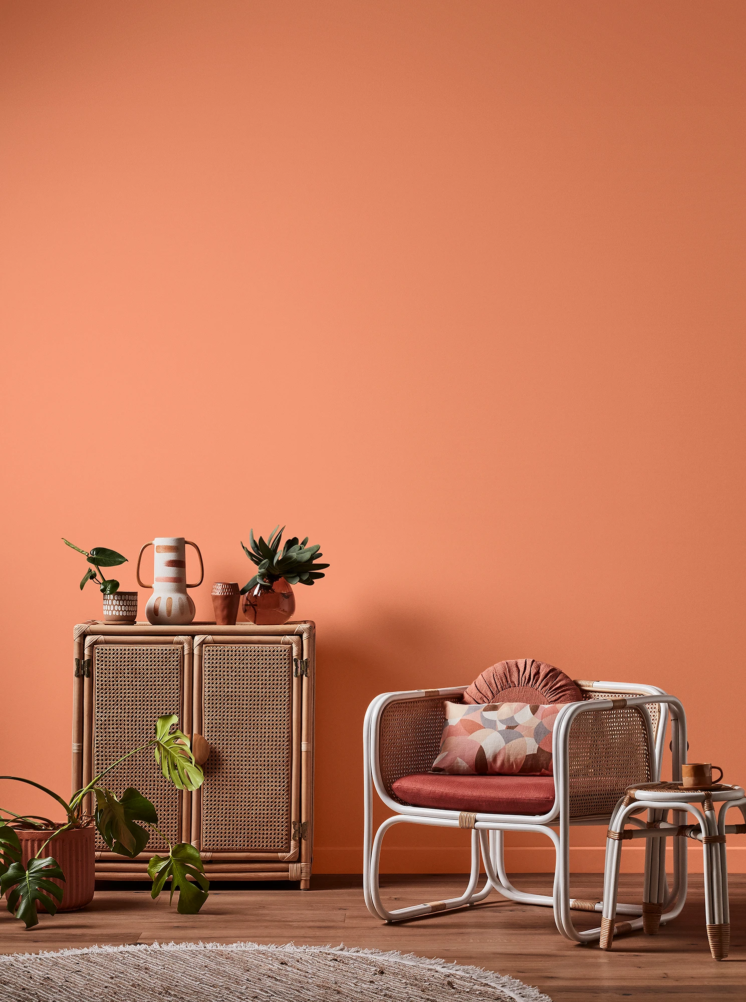 Orange living room with natural rattan cabinet and white rattan table and chair with pink cushions