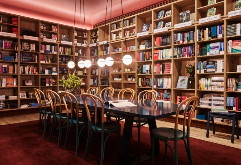 Bookshelves line walles, red ceiling, large table with 10 bentwood chairs, red rug, pendant lighting