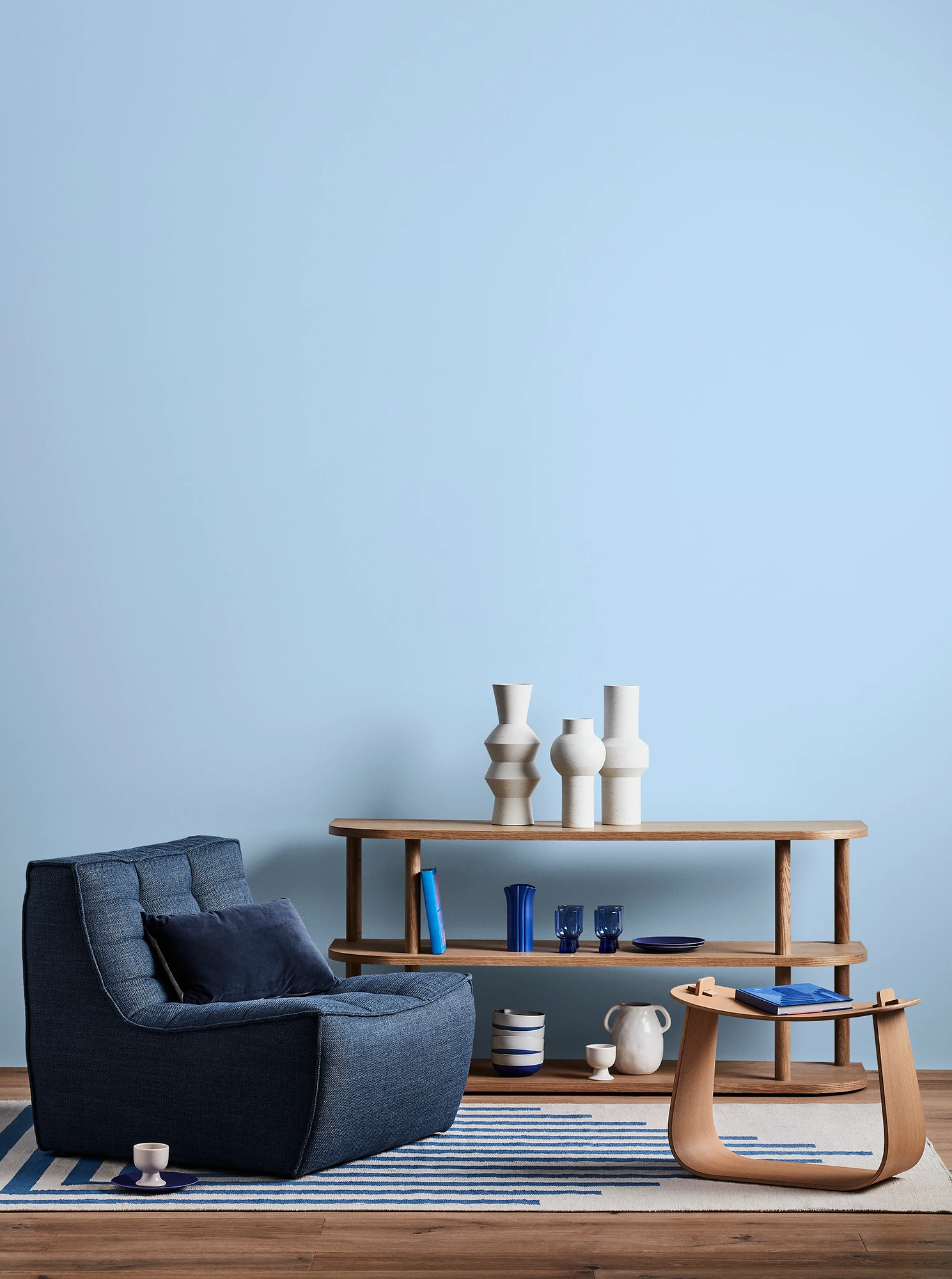 Blue living room with blue armchair and timber side tables.