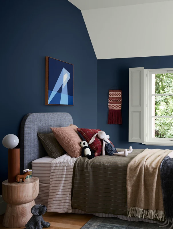 Blue bedroom with white shutters, single bed with plush fabrics.