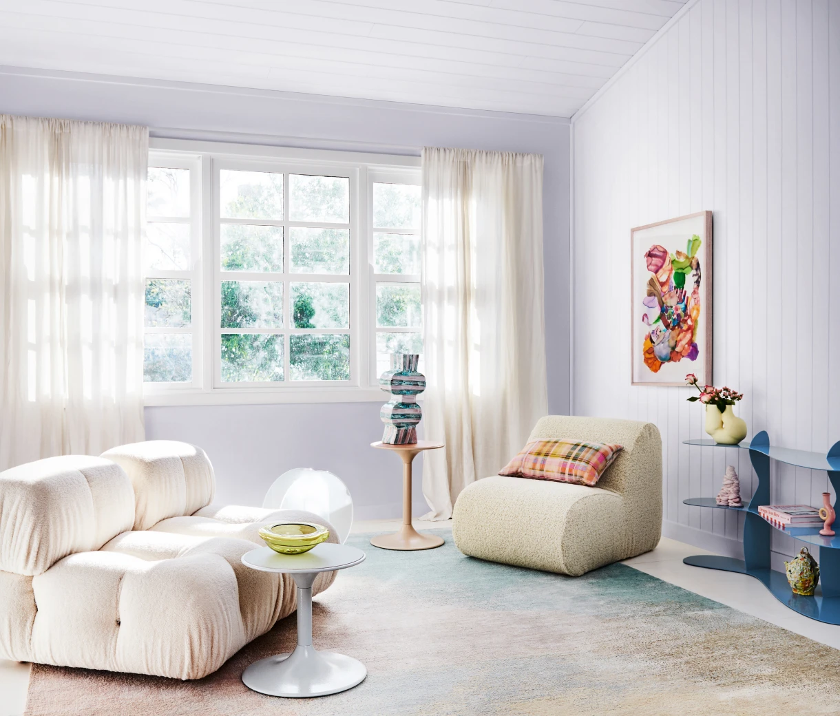 Lilac interior wall with blue shelves and white boucle armchair