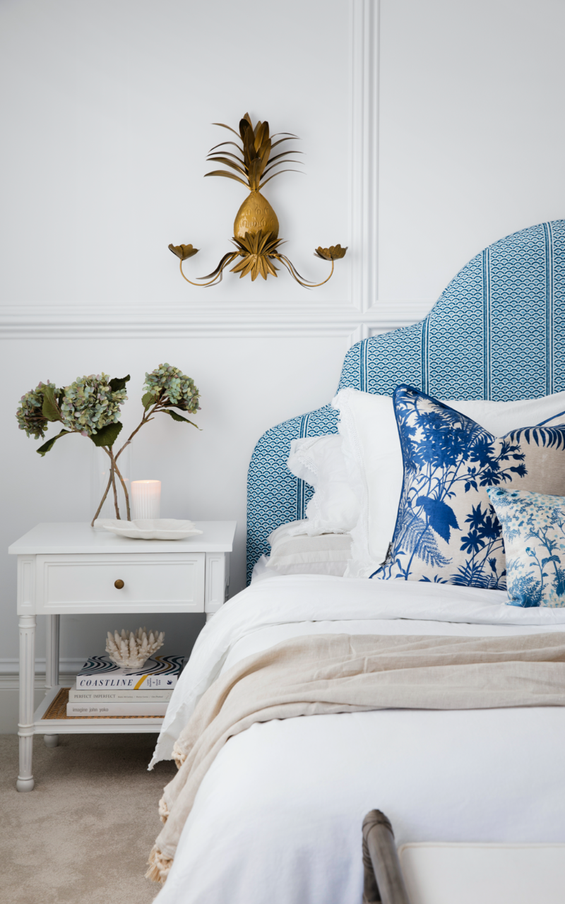 Master bedroom with blue headboard, white linens, white sidetable and walls in Dulux White on White.  Colour Me Hamptons by Three Birds Renovations.