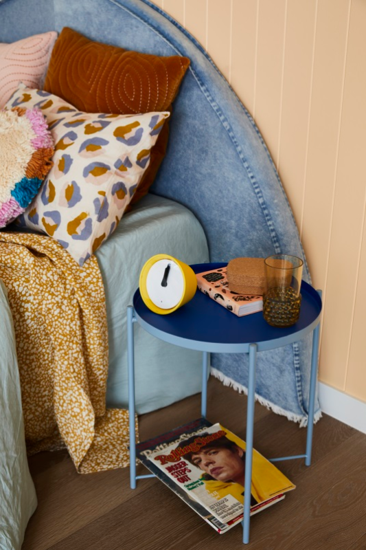 Yellow alarm clock on two-tone blue metal bedside table in room painted in Dulux Apricot Fool.