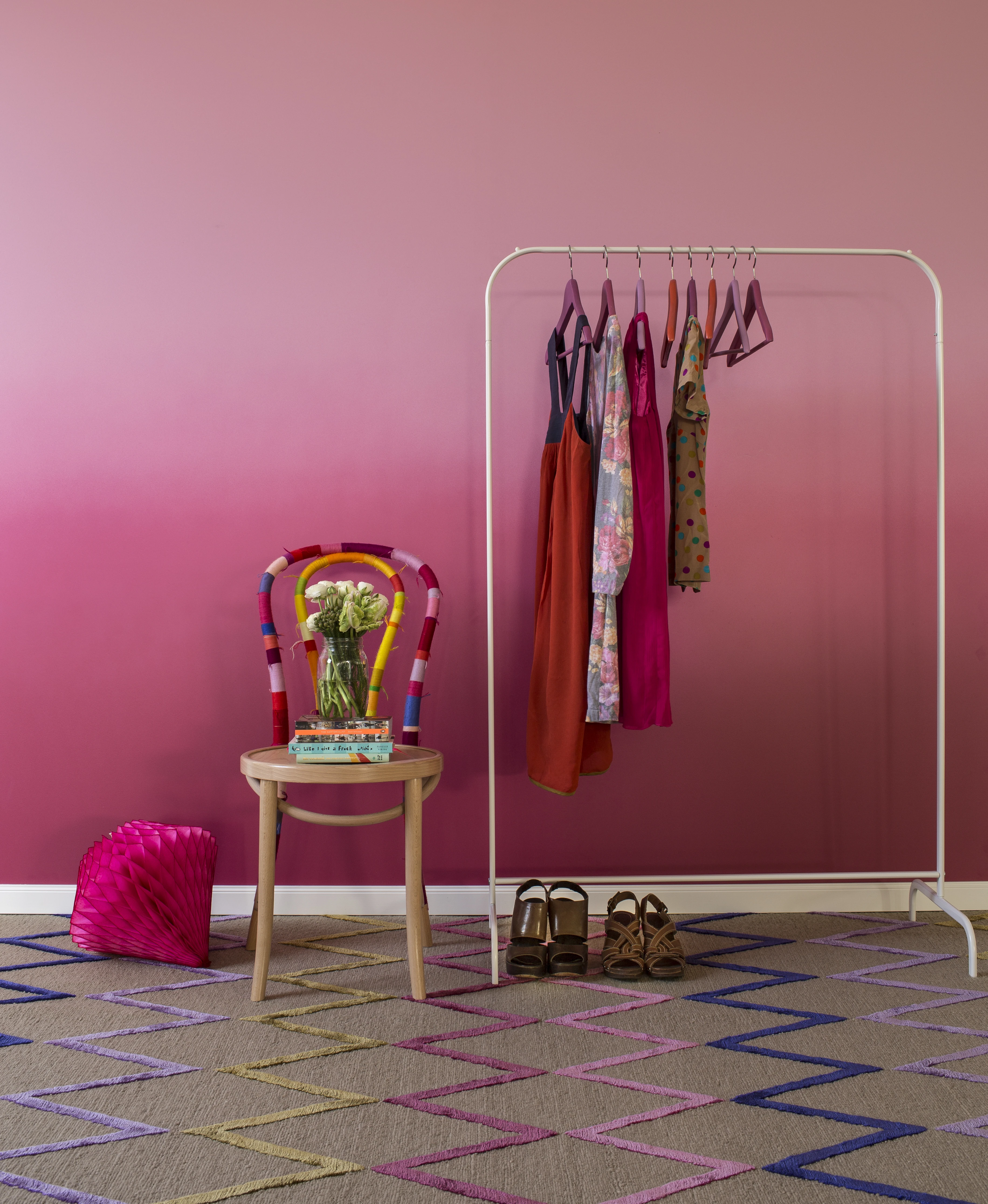 Pink wall with bentwood chair and freestanding clothes rack