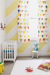 Yellow and white nursey with two cots in either corner and assortnment of toys and cushions.