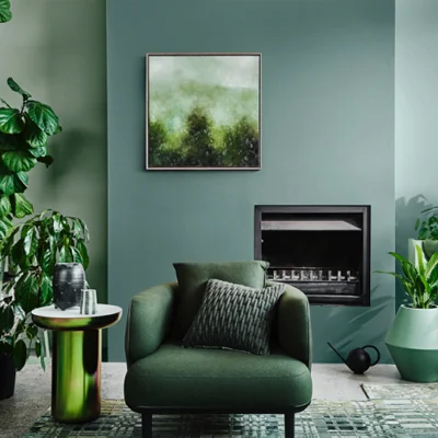 Living room with tonal green shades on walls throughout with wide, modern armchair and fireplace.