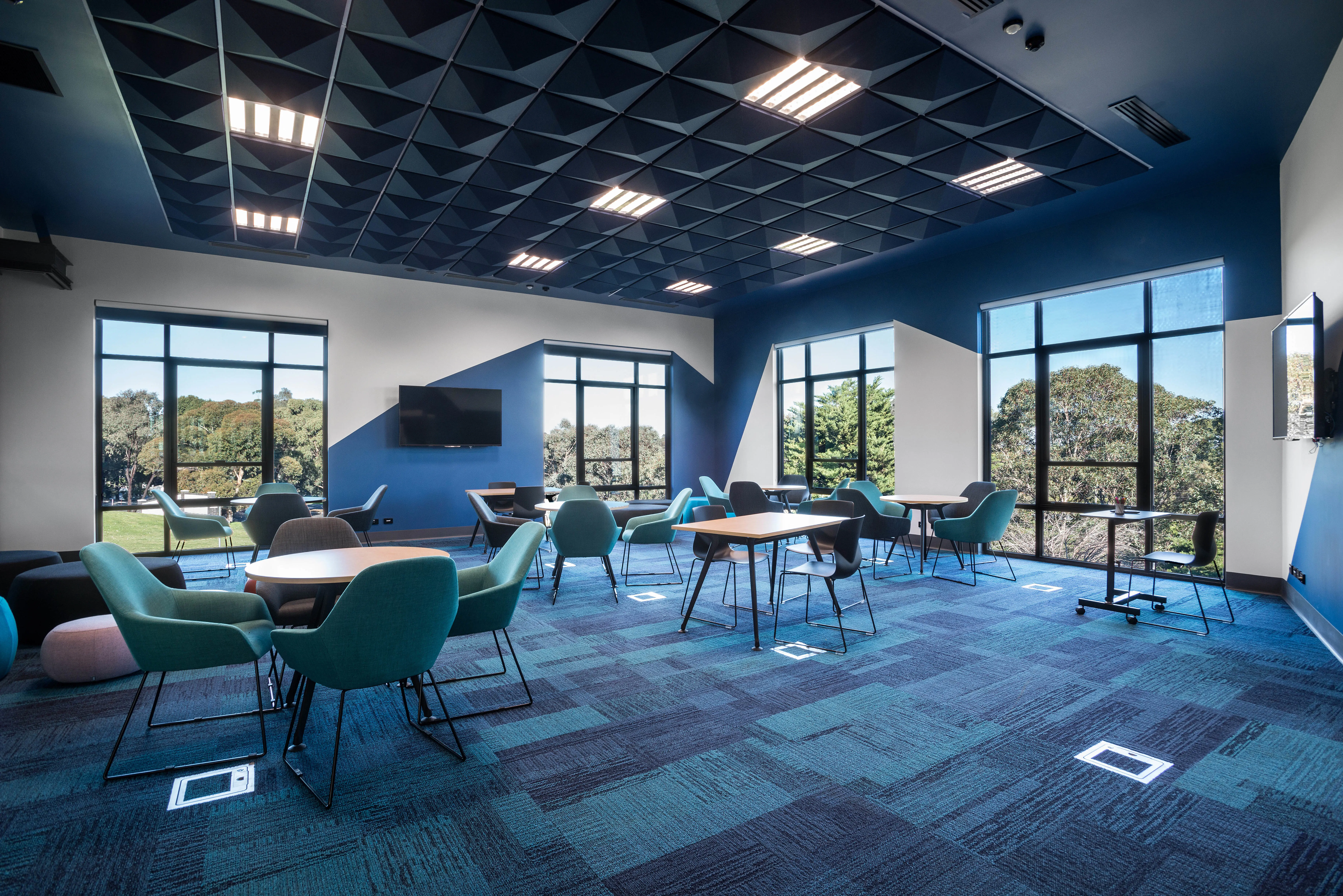 Classroom with carpet in several shades of blue, blue ceiling and blue and white walls.