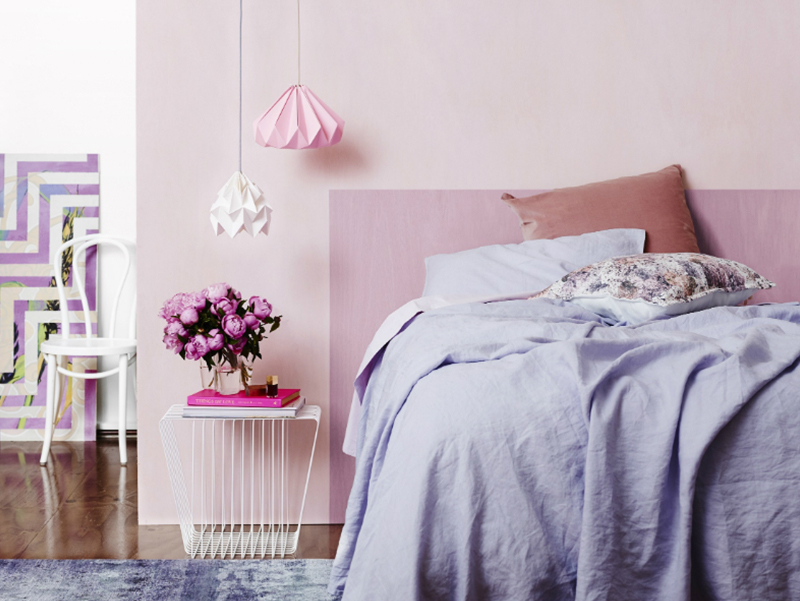 Pink bedroom with pendant lights, pink headboard and purple linens. 