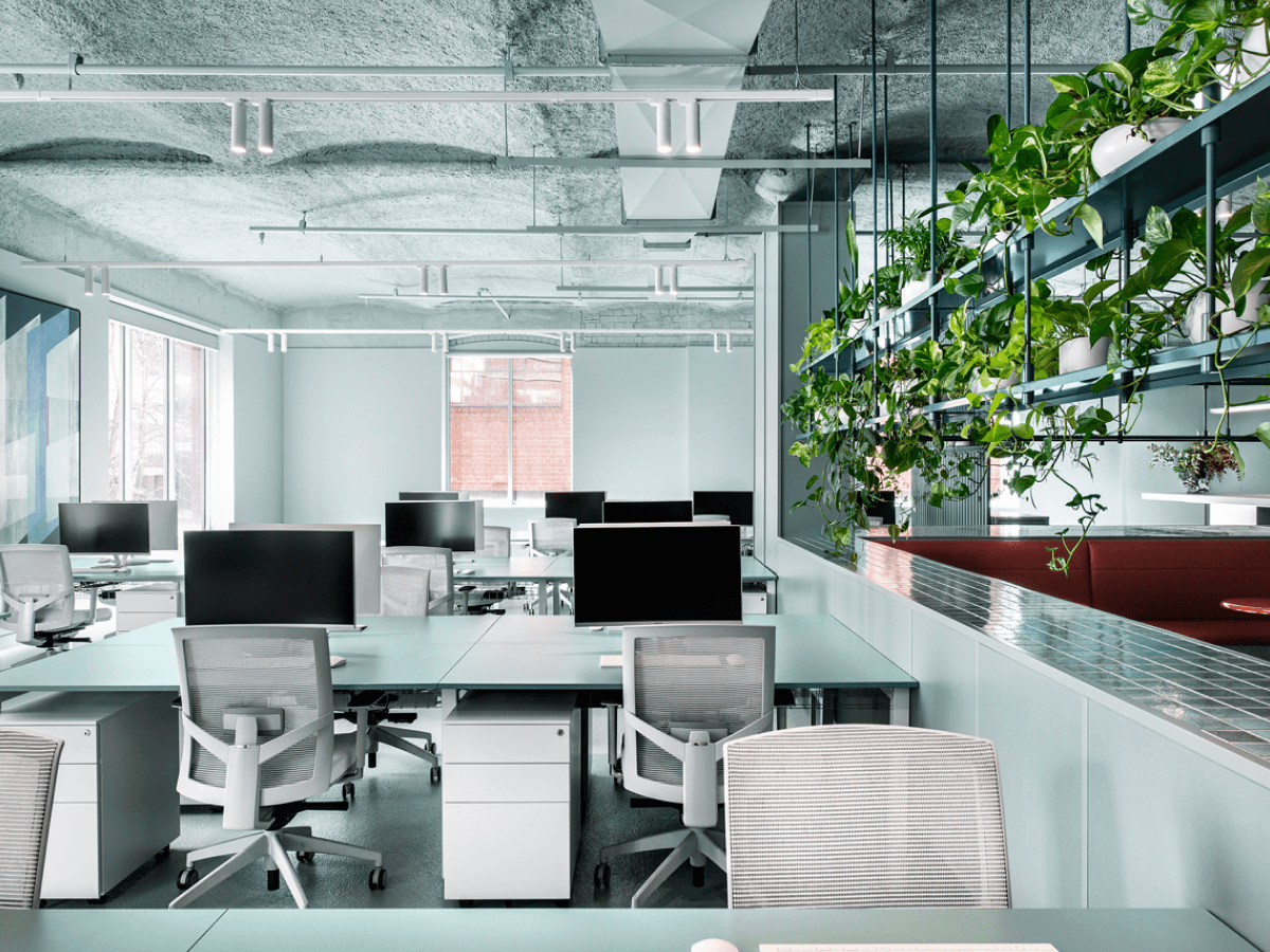 Open plan office with white and soft green desks. Image Credit: Nicole England