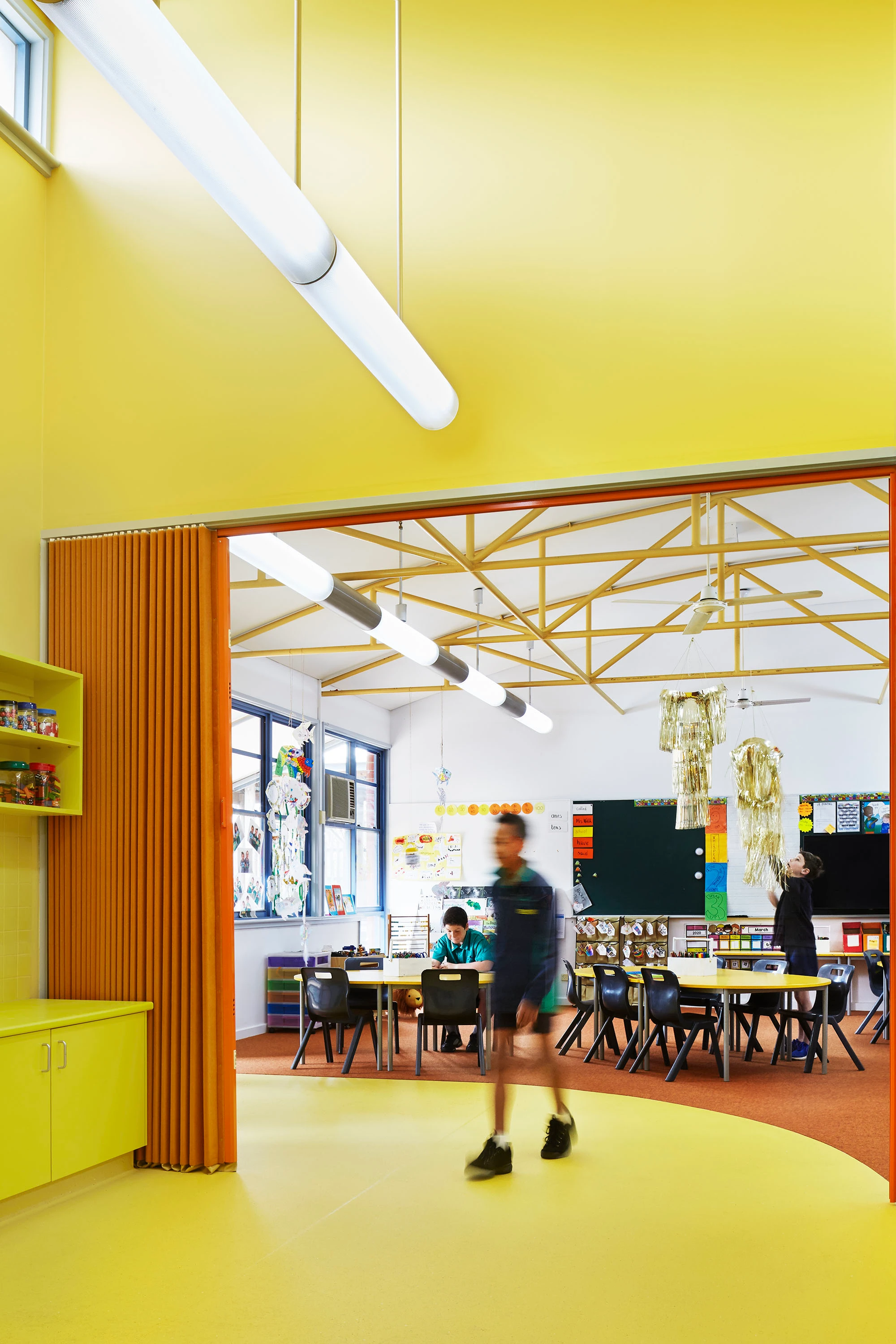 Student walking in yellow-orange classroom 