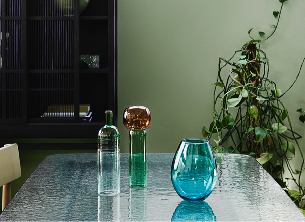 Green dining room, glass-topped table with glass vases and decor.