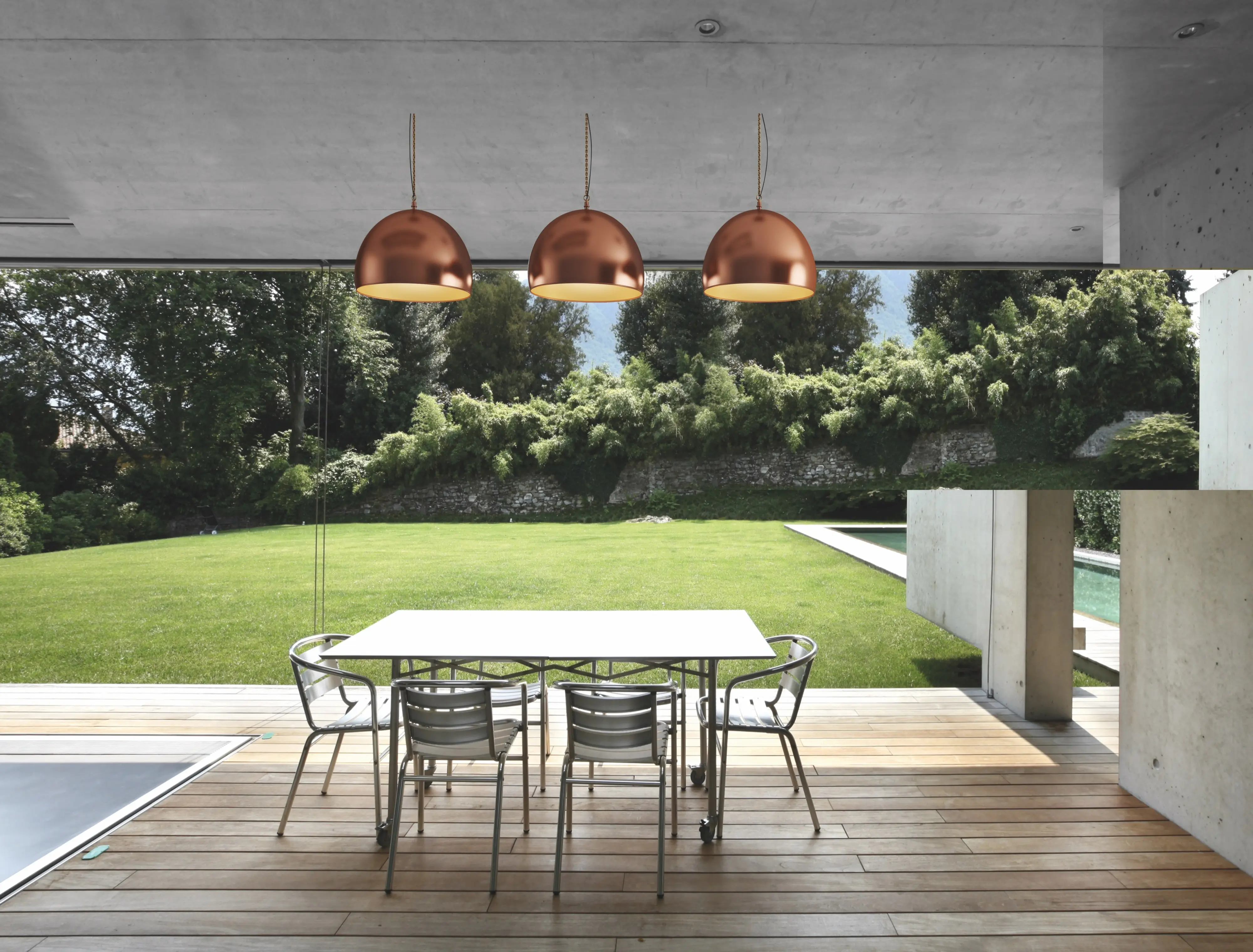 Three brass light shades over alfresco dining table